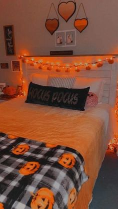 a bedroom decorated for halloween with pumpkins on the bedspread and lights strung across the headboard