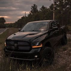 a black ram truck parked on the side of a road next to a wooded area