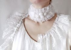 a woman wearing a white dress with flowers on the collar