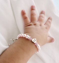 a child's hand with a bracelet on it that has the letter c on it