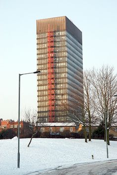 a very tall building sitting in the middle of a snow covered field next to a street light