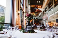 there is a bottle with flowers on it sitting on the table in front of some wine glasses