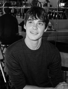 black and white photograph of a young man sitting in front of a chair with his hands on his hips