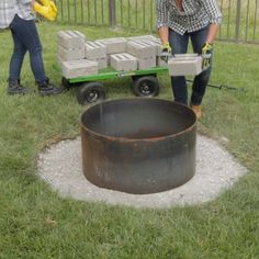 two women are working in the yard with an old wagon and cement blocks on wheels