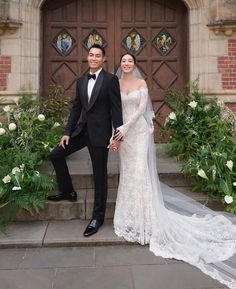 a bride and groom posing for a photo in front of an ornate doorway with flowers