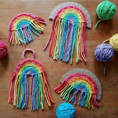 crocheted rainbows and balls of yarn laid out on a wooden table top