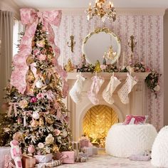 a decorated christmas tree in front of a fireplace with stockings hanging from it's mantle