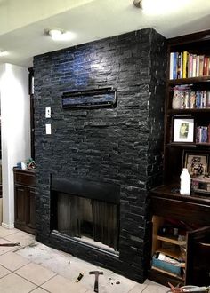 a living room with a black stone fireplace and bookshelves in the corner,