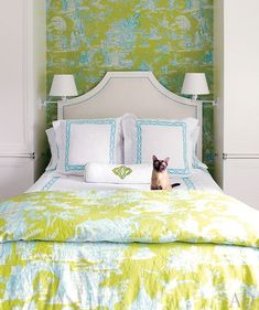 a cat sitting on top of a bed in a room with green and white walls