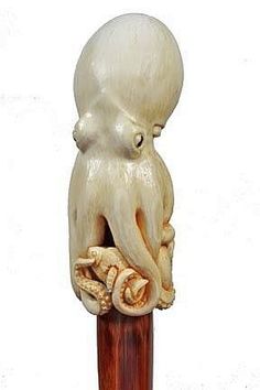 an octopus statue is on top of a wooden pole with shells in it's mouth