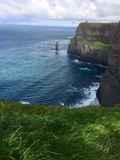 the ocean is blue and green with waves coming in from the cliffs on the far side