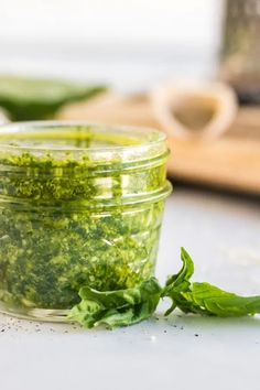 a jar filled with green pestle next to a wooden spoon