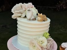 a wedding cake with flowers and an owl figurine on top