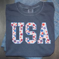 an american flag t - shirt with the word usa printed in red, white and blue flowers