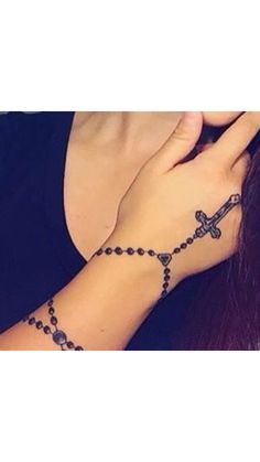 a woman wearing a rosary bracelet with a cross on it's left wrist and her right hand in the middle