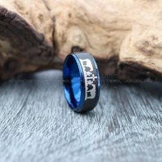 a black and blue ring with the word dad engraved on it sitting next to a piece of wood