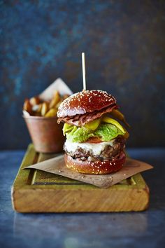 a cheeseburger with lettuce, tomato and pickles on a cutting board