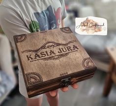 a person holding a wooden box with the words kasiaa jura on it