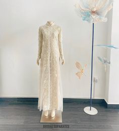 a dress on display in front of a white wall with flowers and butterflies behind it