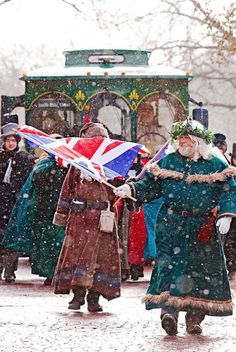 two people walking in the snow with flags and hats on, one holding an union jack flag