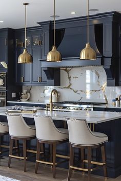 a kitchen with marble counter tops and gold pendant lights hanging from the ceiling over the island