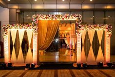 an entrance decorated with flowers and gold drapes for a wedding or reception at the venue