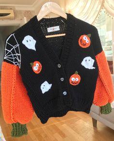 an orange and black cardigan sweater with ghost, pumpkins and web on it