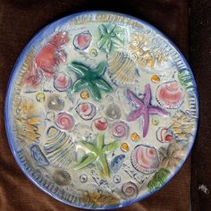 a plate with shells and starfishs on it sitting on a brown table cloth