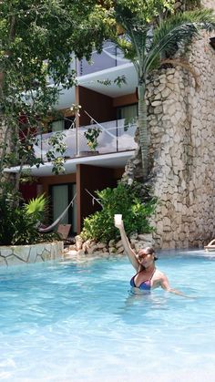 a woman in a swimming pool reaching up to catch a frisbee