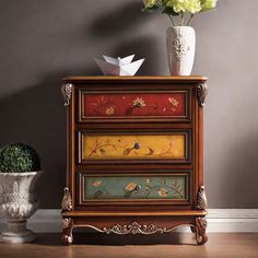 a vase with flowers sitting on top of a chest of drawers next to a flower pot