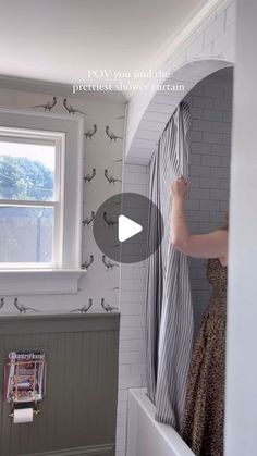 a woman in a dress is opening the shower curtain