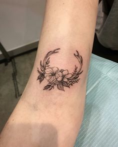 a black and white photo of a woman's arm with a flower tattoo on it