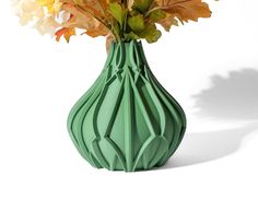 a green vase filled with lots of colorful flowers