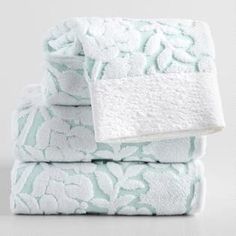 three towels stacked on top of each other in front of a white background with blue flowers