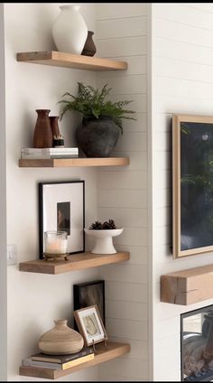 three wooden shelves with plants and pictures on them