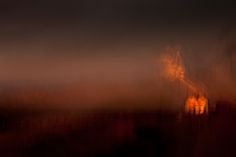 a blurry photo of a clock tower in the distance with an orange light behind it