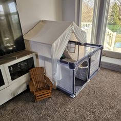 a child's play tent next to a tv in a room with a large window