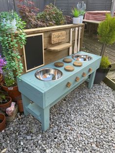 an outdoor dog food station made out of pallet wood and painted blue with three bowls on it