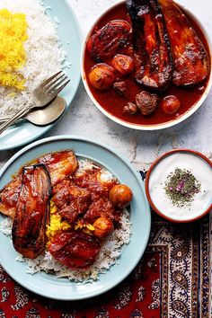 two plates with meats and rice next to some other dishes on a table top