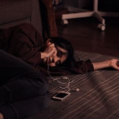 a woman laying on the floor with her head in her hands while listening to music