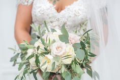 a bride holding a bouquet of flowers and greenery