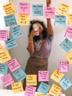 a woman standing in front of a mirror covered in post it notes