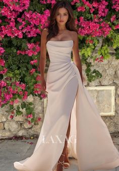 a woman standing in front of pink flowers wearing a white dress and high heeled sandals