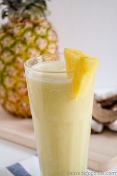 a pineapple drink is garnished with a slice of lemon on the side