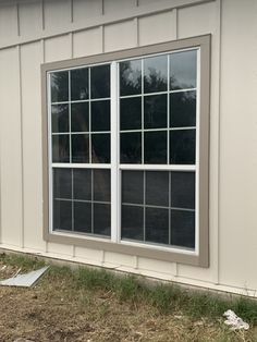 a dog is standing in front of a window on the side of a house that has been painted white