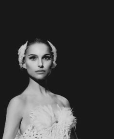 a black and white photo of a woman in a dress with feathers on her head