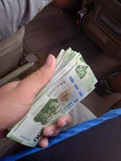 a person holding money in their hand on the back seat of a car or truck