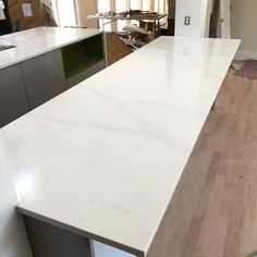 an empty kitchen with white marble counter tops