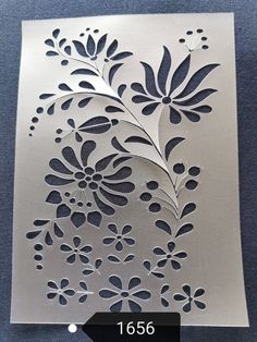 a metal sheet with flowers and leaves cut out on it's side, in the shape of a flower