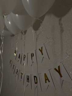 balloons and streamers are hanging from the ceiling in front of a happy birthday banner